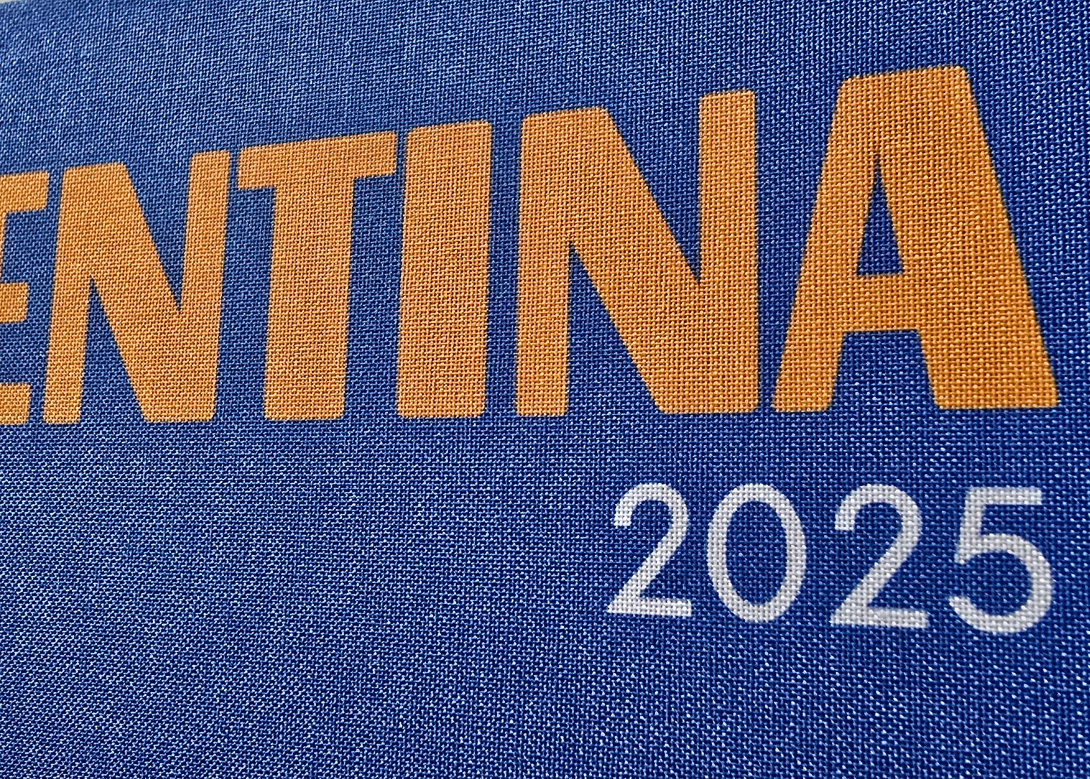 Blue sign with 'ARGENTINA 2025' text on a fabric background