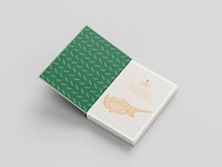 Two notebooks, one green with a pattern and one white with a design, on a light gray background.