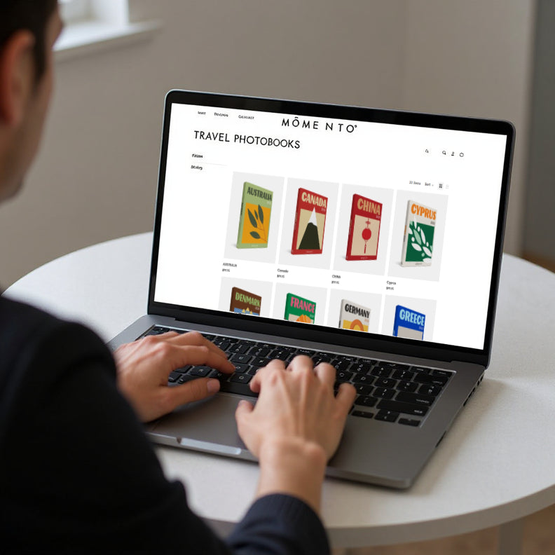 Person using a laptop with a travel photobook website displayed on the screen.