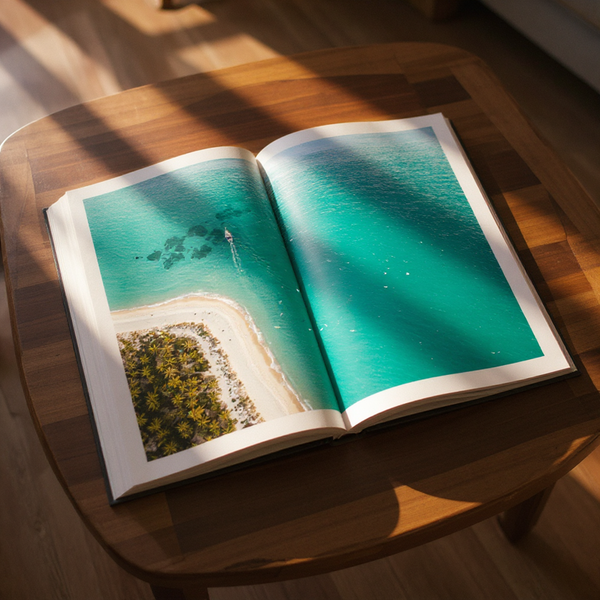 Open book on a wooden table showing an aerial view of a tropical island.